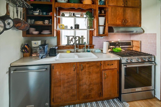 kitchen featuring open shelves, a sink, appliances with stainless steel finishes, wall chimney exhaust hood, and backsplash