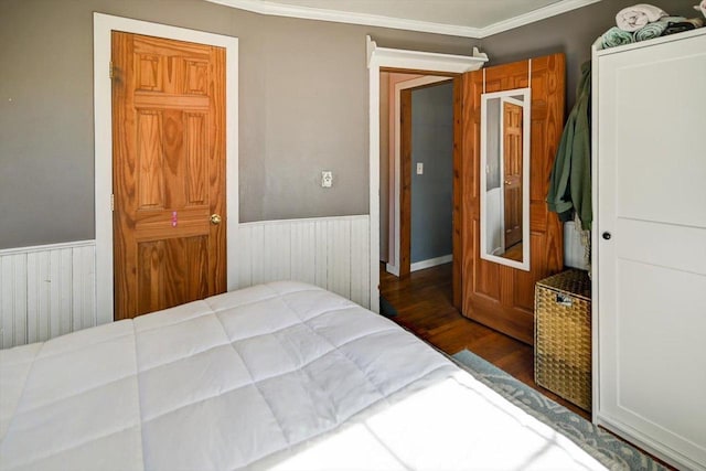 bedroom with a wainscoted wall, wood finished floors, and ornamental molding