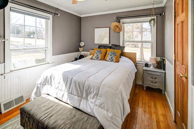 bedroom with visible vents, multiple windows, wood finished floors, and ornamental molding