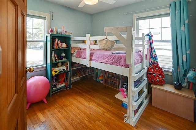 bedroom featuring a ceiling fan, multiple windows, and wood finished floors