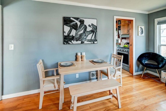 dining area featuring light wood-type flooring, baseboards, and crown molding