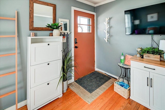 foyer entrance featuring baseboards, light wood-type flooring, and ornamental molding