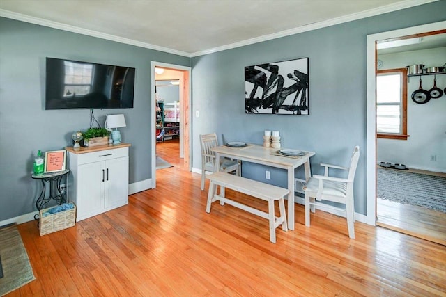 dining space with light wood finished floors, baseboards, and ornamental molding