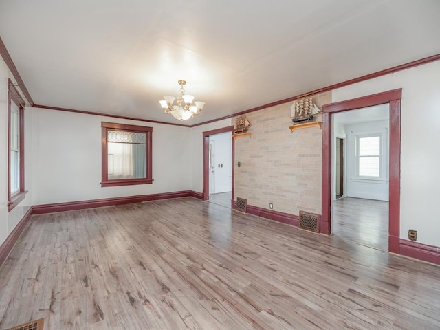 spare room featuring ornamental molding, wood finished floors, visible vents, and a notable chandelier