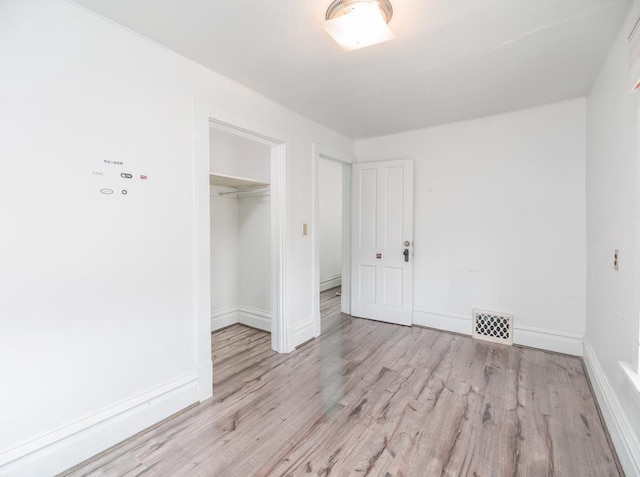 unfurnished bedroom featuring baseboards, a closet, visible vents, and wood finished floors