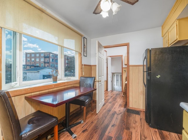 dining space featuring dark wood-style flooring, a wainscoted wall, and ceiling fan