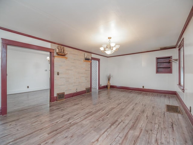 spare room featuring an inviting chandelier, visible vents, wood finished floors, and ornamental molding