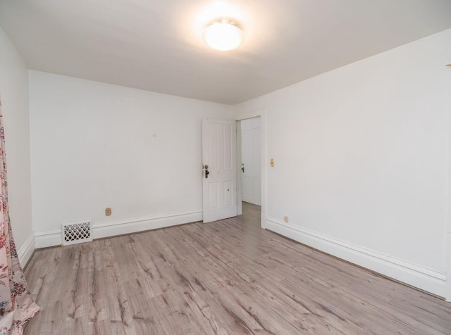 unfurnished room featuring visible vents, baseboards, and wood finished floors