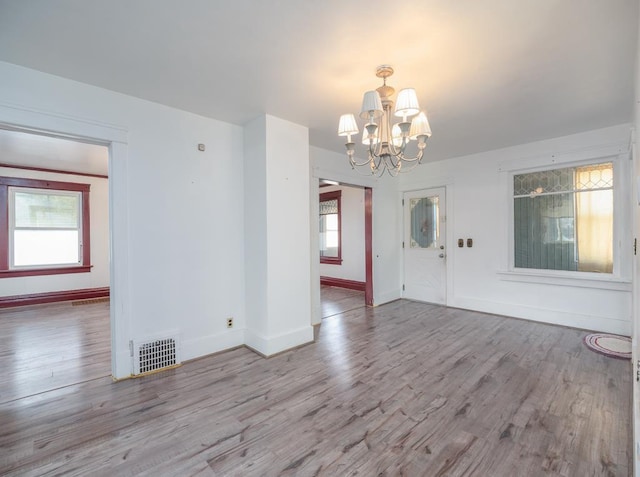 interior space featuring a notable chandelier, baseboards, visible vents, and wood finished floors