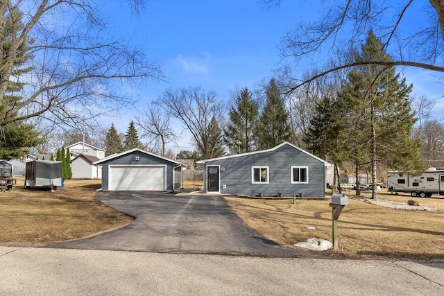 single story home with a detached garage, aphalt driveway, and an outbuilding