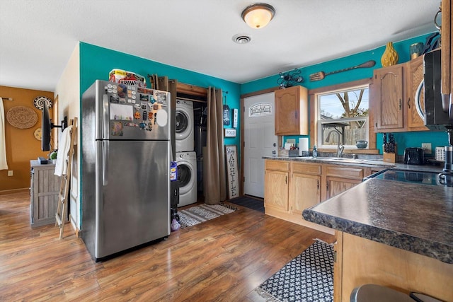 kitchen with stainless steel appliances, visible vents, light wood-style floors, stacked washing maching and dryer, and dark countertops