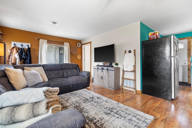 living area featuring visible vents and wood finished floors