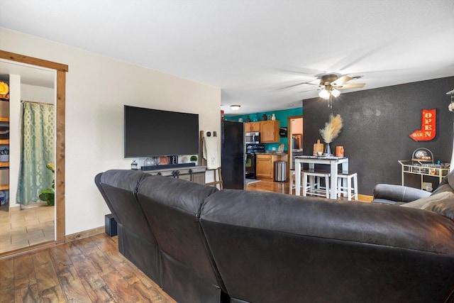 living room featuring dark wood-style floors, a ceiling fan, and baseboards