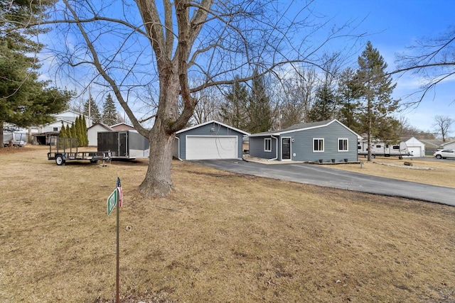 view of front of home featuring a garage, a front lawn, and an outbuilding