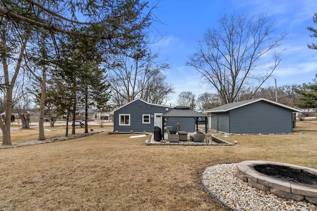 back of property featuring a gazebo, a yard, and an outdoor living space with a fire pit