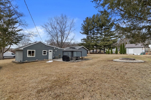 view of yard featuring a fire pit, a gazebo, central AC unit, and an outbuilding