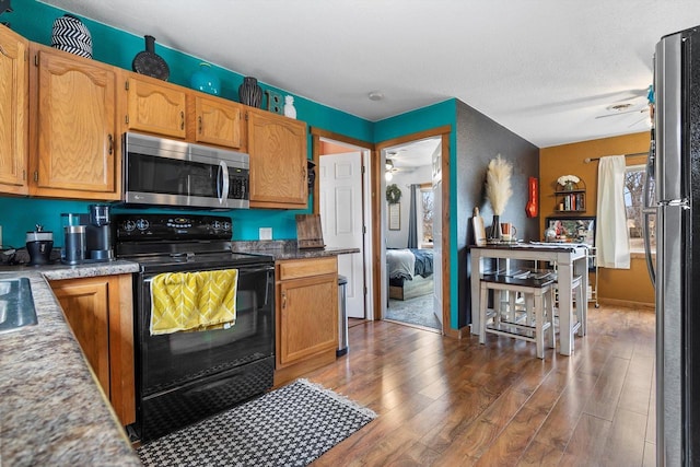 kitchen with appliances with stainless steel finishes, dark wood-type flooring, and a ceiling fan