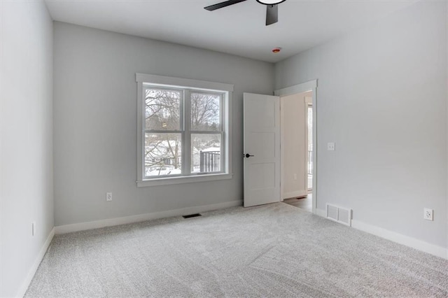 carpeted spare room with ceiling fan, visible vents, and baseboards