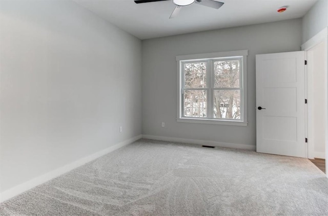 carpeted spare room featuring ceiling fan, visible vents, and baseboards