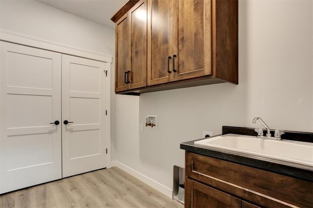 washroom with hookup for a washing machine, cabinet space, electric dryer hookup, light wood-type flooring, and baseboards