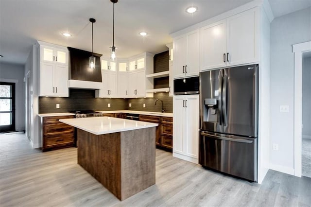 kitchen featuring a sink, white cabinetry, stainless steel refrigerator with ice dispenser, backsplash, and custom range hood