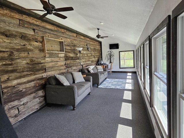 unfurnished living room with a textured ceiling, dark colored carpet, vaulted ceiling, and ceiling fan