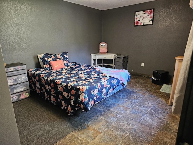 bedroom with stone finish flooring and a textured wall