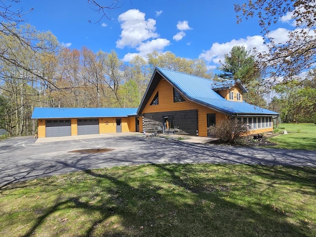 view of side of home featuring a garage, a yard, aphalt driveway, and metal roof