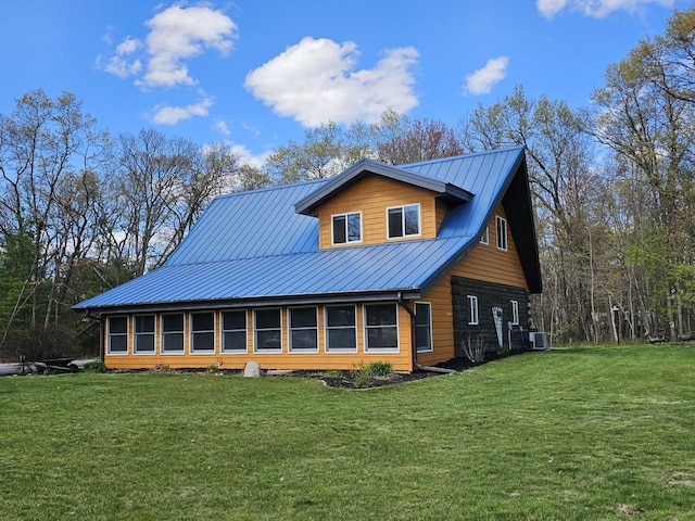 view of side of home featuring cooling unit, a standing seam roof, a yard, and metal roof