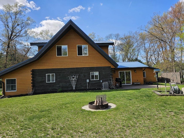 rear view of house with a patio area, a fire pit, cooling unit, and a yard