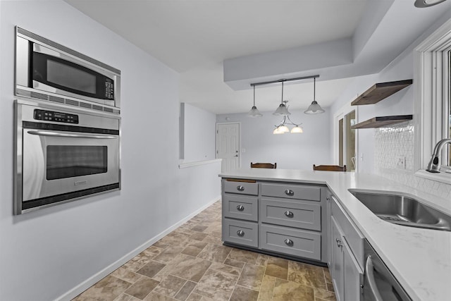 kitchen featuring gray cabinetry, stainless steel appliances, a peninsula, a sink, and open shelves