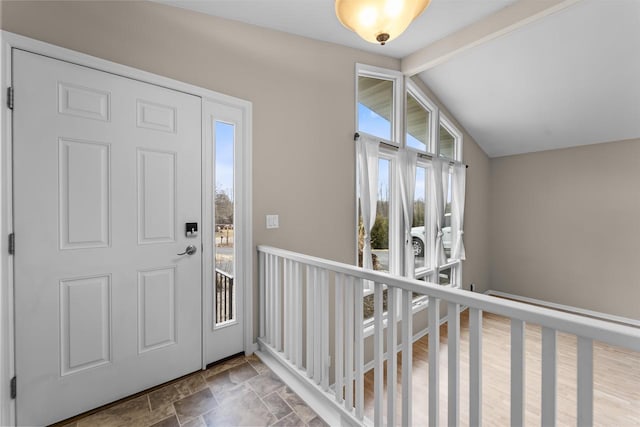 foyer featuring vaulted ceiling with beams and stone finish flooring