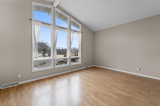 spare room featuring baseboards, visible vents, vaulted ceiling with beams, and light wood finished floors