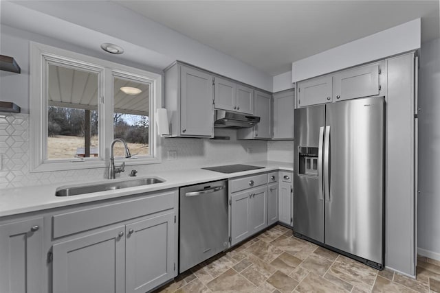 kitchen featuring gray cabinetry, appliances with stainless steel finishes, a sink, and under cabinet range hood