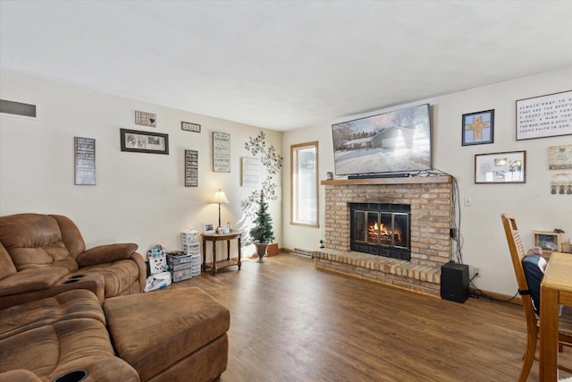 living room with visible vents, a fireplace, baseboards, and wood finished floors