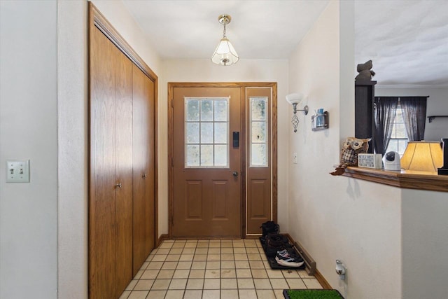 doorway to outside featuring a healthy amount of sunlight, light tile patterned floors, and baseboards