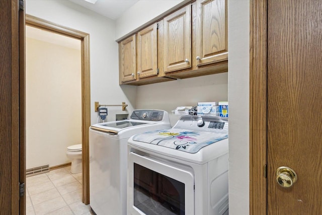 washroom with light tile patterned flooring, separate washer and dryer, visible vents, baseboards, and cabinet space