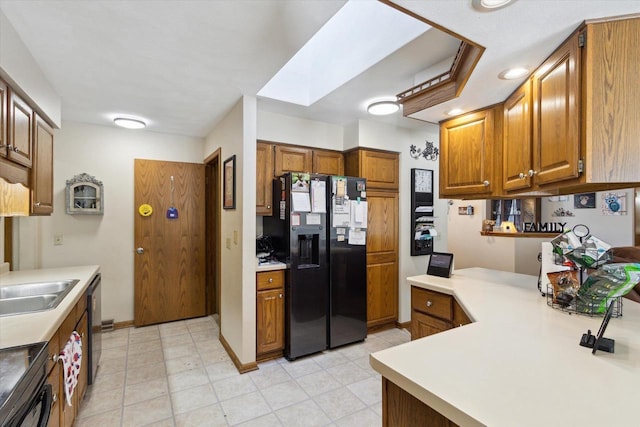 kitchen featuring light countertops, a skylight, brown cabinets, and black fridge with ice dispenser