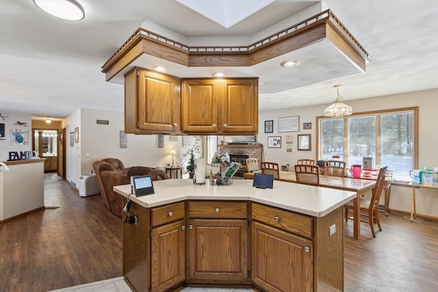 kitchen with open floor plan, light countertops, a fireplace, and wood finished floors