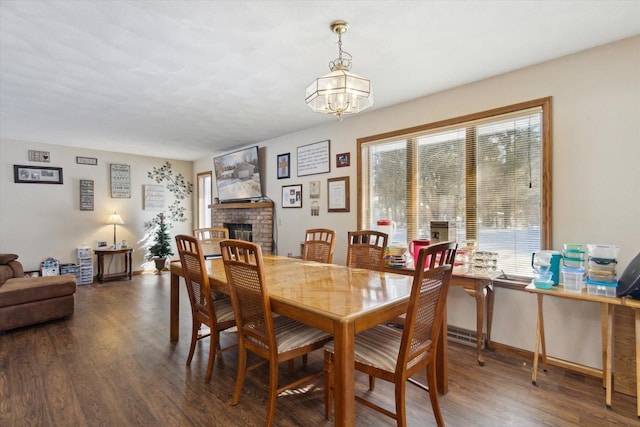 dining space with baseboards, a fireplace, wood finished floors, and an inviting chandelier