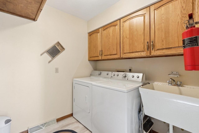 washroom featuring a sink, visible vents, baseboards, cabinet space, and washing machine and clothes dryer