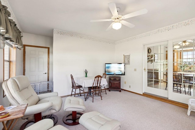 carpeted living area featuring ceiling fan and baseboards