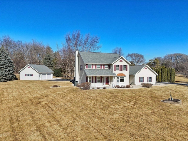 view of front facade featuring an outbuilding, covered porch, a chimney, and a front lawn