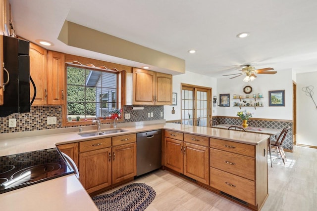 kitchen with dishwasher, backsplash, a peninsula, light countertops, and a sink