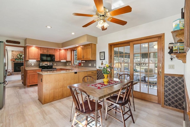 kitchen with stainless steel appliances, a peninsula, a sink, light countertops, and wainscoting