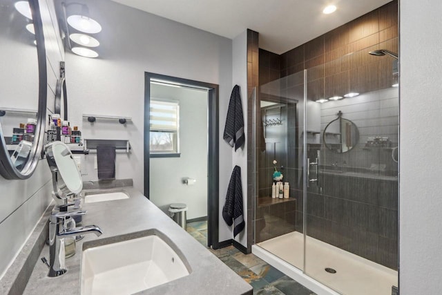 bathroom featuring a stall shower, stone finish floor, a sink, and double vanity