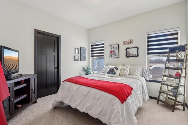 carpeted bedroom featuring multiple windows and baseboards