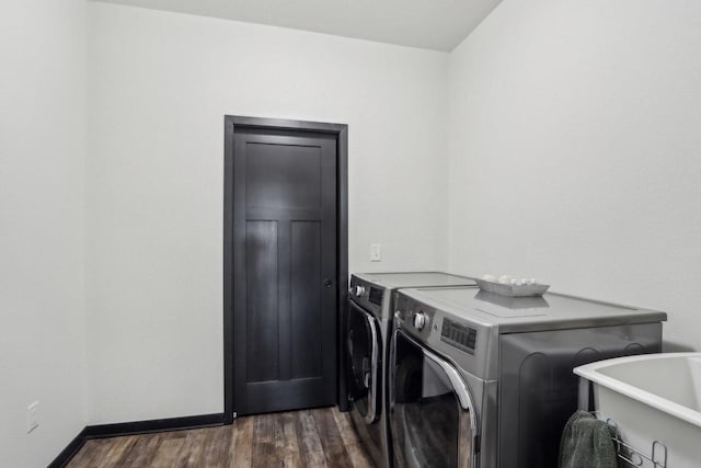 laundry area with laundry area, baseboards, dark wood-style flooring, washing machine and dryer, and a sink