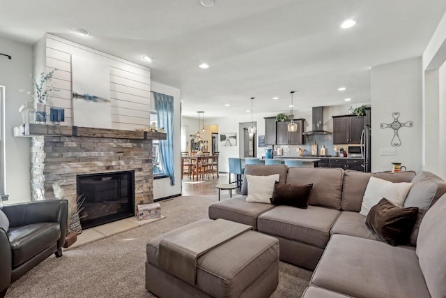 living room featuring recessed lighting, light carpet, and a stone fireplace