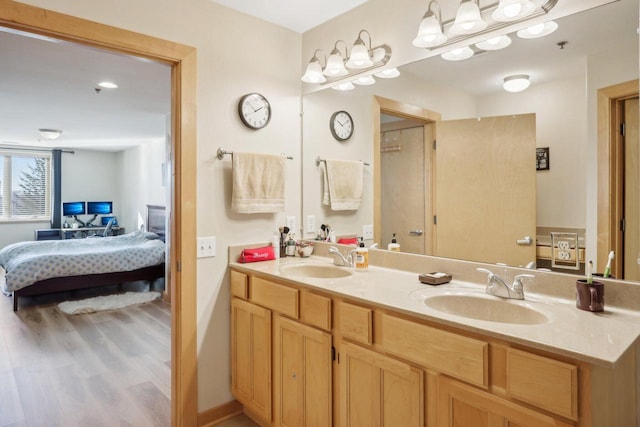 full bathroom with connected bathroom, double vanity, a sink, and wood finished floors